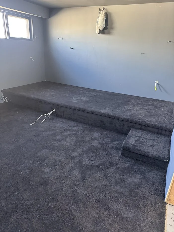 Dark charcoal cut pile carpet seamlessly covering the theatre room floor and riser platform