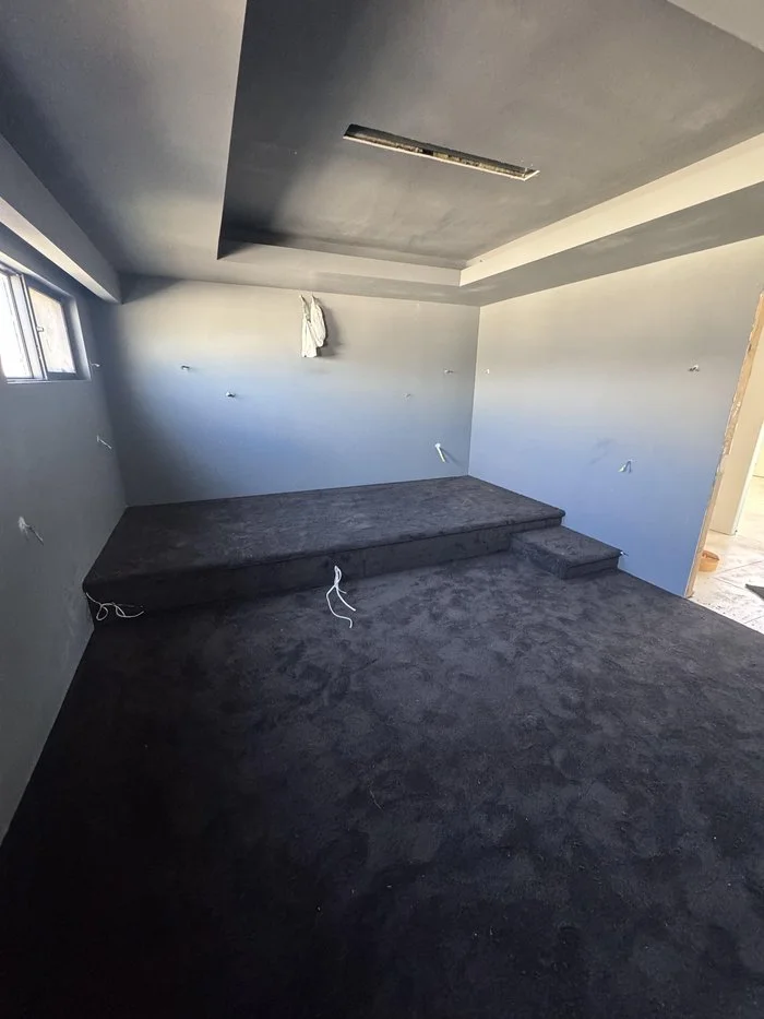 Home theatre room in Melbourne with two-level tiered seating riser fully covered in dark charcoal carpet