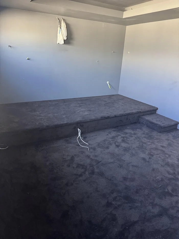 Step edge of the carpeted seating riser showing seamless wrap with bullnosed finish and no visible fixings