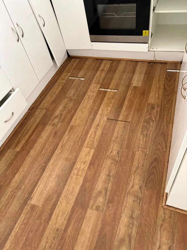 Water-damaged laminate flooring with swollen joins in a Melbourne rental kitchen